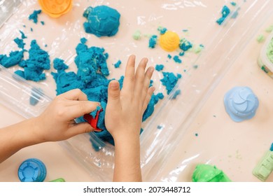 Kinetic Sand. Children's Hands Play With Multi-colored Polymer Sand.