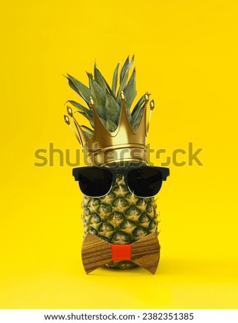 The king of all fruits. Creative tropical summer layout made of pineapple with crown, sunglasses and bow tie on light yellow background. Minimal concept. Trendy ananas idea. Pineapple aesthetic.