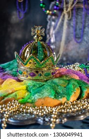 king cake with crown surrounded by mardi gras beads