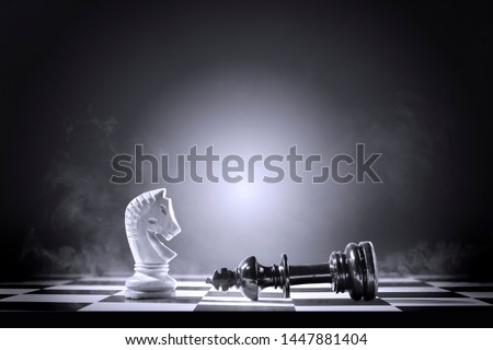 King chess piece defeating by knight chess piece on the chessboard