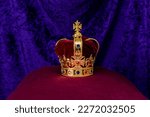 King Edwards Crown to be used by King Charles III for his Coronation sits on a purple pillow with a purple background. 