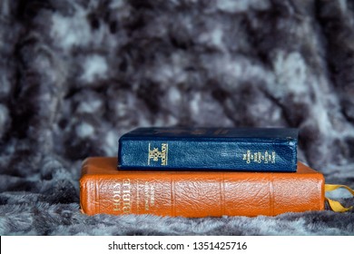 King James Version Of The Bible With The Book Of Mormon On A Gray, Textured Background.