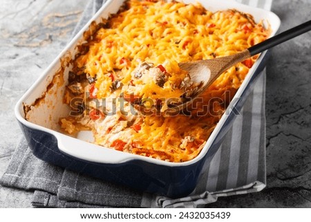 King Ranch Chicken Casserole, Tex-Mex dish of layered tortilla pieces and chicken in a spicy, cheesy sauce close-up in a baking dish on a marble table. Horizontal
