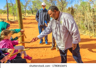 Kings Creek Station, Australia - Aug 21, 2019: Aboriginal Australian Man Shows A Wooden Percussion Instrument Used By Luritja And Pertame People In Central Australia, To People In Tour.