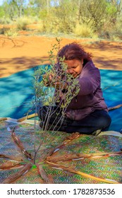 Kings Creek Station, Northern Territory, Australia - Aug 21, 2019: Australian Aboriginal Woman Making A Ritual On A Bush Painting. Karrke Aboriginal Cultural Experience Tour In Australian Outback.