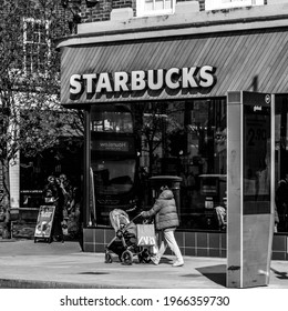 Kingston Upon Thames, London UK, April 19 2021, Woman Walking Past A Starbucks Coffee Shop Pushing A Baby Pushchair Or Stroller