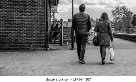 Kingston Upon Thames Surrey London UK May 07 2021, Anonymous Middle Aged Couple Walking On A Pathway Carrying Shopping Bags Together