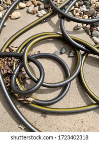 Kinked, Twisted, And Knotted Black Garden Hose On Rock