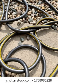 Kinked, Twisted, And Knotted Black Garden Hose On Rock