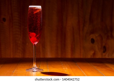 Kir royal cocktail with cherry on wood background