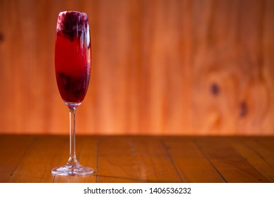 Kir royal cocktail with cherry on wood background.
