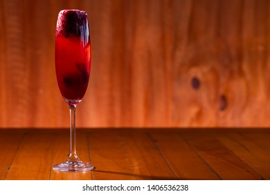 Kir royal cocktail with cherry on wood background.

