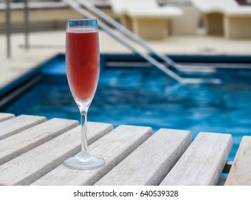 Kir royal cocktail in flute glass near swimming pool on summer vacation.