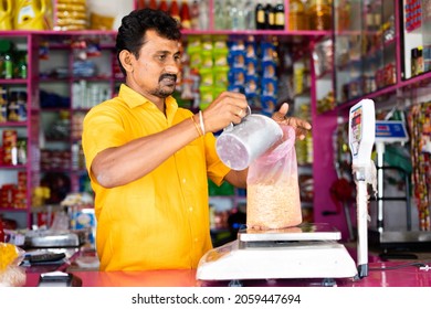 Kirana Or Grocery Merchant Busy Measuring Weight Of Pigeon Pea On Weighing Scale Before Giving To Customer - Concept Of Small Business And Occupation