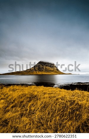 Kirkjufell Mountain with Cloud Cap Reflected across Fjord with Golden Grass Foreground, Snaefellsnes Iceland