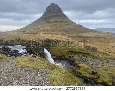 Kirkjufell mountain with waterfall and dramatic cloudy sky, Snaefellsnes, Iceland