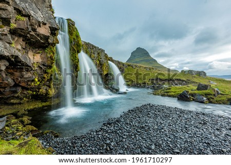 Kirkjufellsfoss in the Icelandic summer with Kirjufell mountain in the background. Dramatic sky - long time exposure