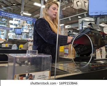 Kirkland, WA / USA - Circa April 2020: Cashier Behind A Plexiglass Wall At A Checkout Counter Inside A QFC Grocery Store During The Coronavirus Outbreak.