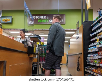 Kirkland, WA / USA - Circa April 2020: Cashier Behind A Plexiglass Wall At A Checkout Counter Inside A Fred Meyer Grocery Store During The Coronavirus Outbreak