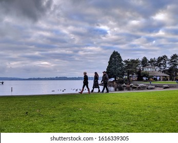 Kirkland, WA / USA - circa December 2019: People walking by the beach at the Kirkland Marina at Lake Washington, ducks and a large gazebo in the background.