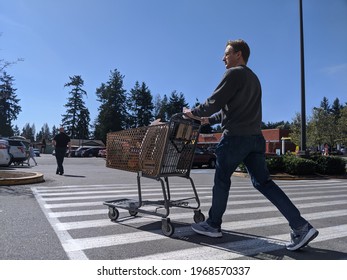 Kirkland, WA USA - Circa May 2020: Street View Of A Man With A Grocery Cart Leaving A Safeway Store On A Sunny Day.