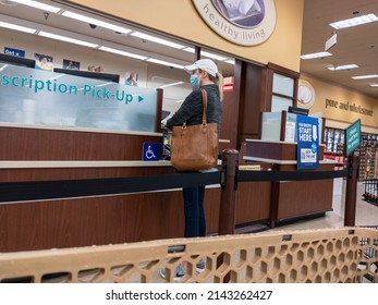 Kirkland, WA USA - Circa October 2021: View Of A Woman In A Baseball Hat Picking Up A Prescription At A Pharmacy Inside A Safeway Grocery Store