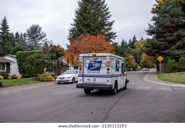Kirkland, WA USA\
- circa October 2021: Street view of a USPS mail truck, making its\
rounds in a residential\
area.