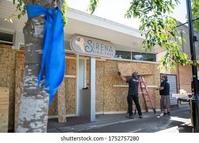 Kirkland, Washington / USA - June 1 2020:  Handymen Boarding Up A Gelato Shop Before Protests Against Police Violence, With A Ribbon Supporting Essential Workers In The Foreground