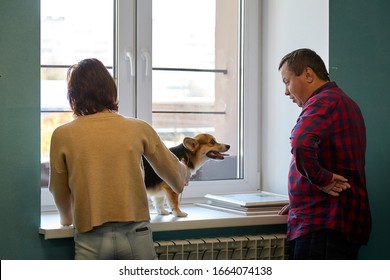 Kirov, Russia - September 13, 2019: Professional Vet Doctor Examines A Small Adult Dog With Her Female Owner. Caucasian Fat Plump Male Vet Works In A Veterinary Clinic With Patient