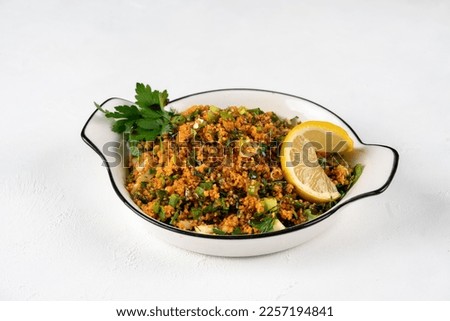 Kisir, a traditional vegan salat prepared from bulgur wheat, tomato, parsley, olive oil and spices. Top view of a kisir salat on the wooden table.