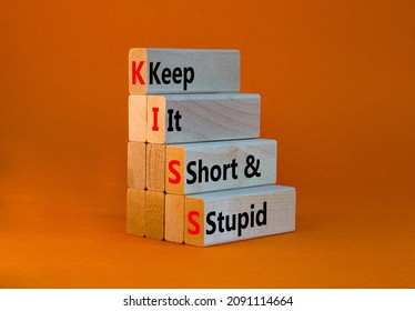 KISS keep it short and stupid symbol. Concept words KISS keep it short and stupid wooden blocks. Beautiful orange table, orange background. Business KISS keep it short and stupid concept. Copy space.