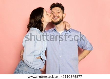 Kiss. Married couple of young and happy man and woman isolated on pink trendy color background. Human emotions, youth, love and lifestyle concept.