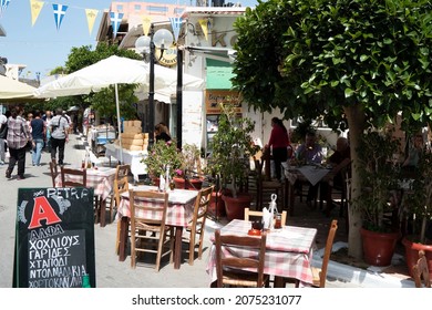 Kissamos, Crete - Greece - April 29 2016 :  Pavement Taverna In A Busy Square In This Bustling Greek Town  Easter Celebrations With People Enjoying The Holiday