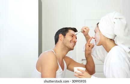 Kissing Joyful Couple With Bathrobe And Beauty Mask Making Wellness At Home