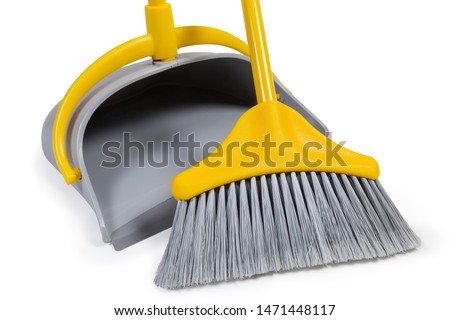 Kit of the yellow plastic broom with gray bristles for sweeping floors and dustpan on a white background, working parts close-up
