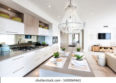 Kitchen with adjoining snack counter set for four people and living area with a wall hanging T.V.