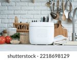 Kitchen appliances and devices. Electric smart rice cooker on wooden counter-top in the kitchen with brown rice
