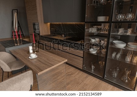 kitchen area in a chic expensive interior of a luxury home with a dark black and brown modern design with wood trim and led light