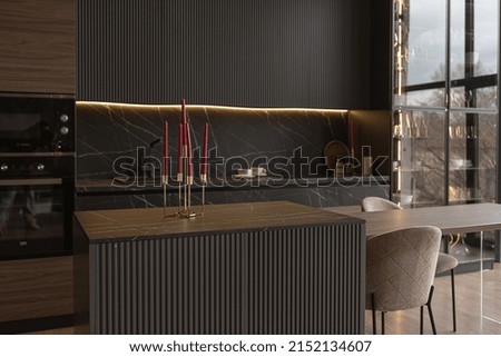 kitchen area in a chic expensive interior of a luxury home with a dark black and brown modern design with wood trim and led light