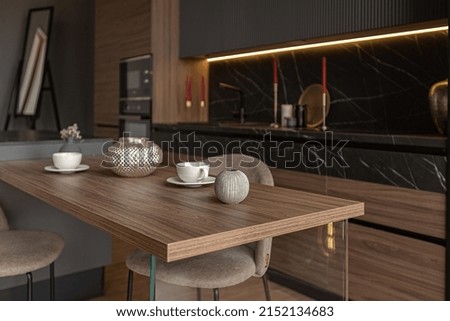 kitchen area in a chic expensive interior of a luxury home with a dark black and brown modern design with wood trim and led light