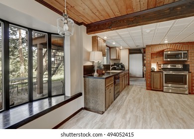 Kitchen Area With Red Brick Wall And Built In Appliances. Empty Window Seat Overlooking Back Yard. Large Wooden House Interior.  Northwest, USA