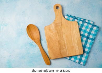 Kitchen Background With Cutting Board, Tablecloth And Spoon Over Blue Stone Counter. View From Above