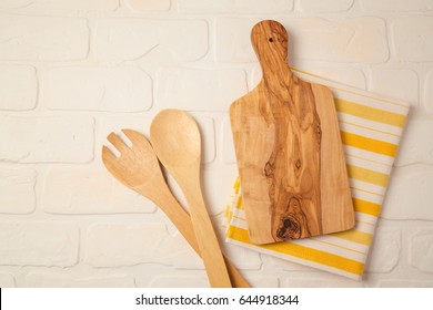 Kitchen Background With Cutting Board, Tablecloth And Spoon Over Brick Counter. View From Above