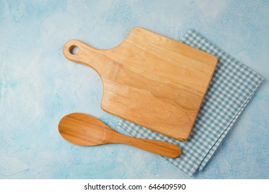 Kitchen Background With Cutting Board, Tablecloth And Spoon Over Blue Stone Counter. View From Above