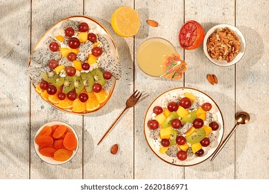 Kitchen background with fruit salads with soft grain cottage cheese, yogurt, dragon fruit, kiwi, mango, oranges, nuts, orange juice and grapes. Healthy light breakfast with ingredients,
