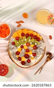Kitchen background with fruit salads with soft grain cottage cheese, yogurt, dragon fruit, kiwi, mango, oranges, nuts, orange juice and grapes. Healthy light breakfast with ingredients,