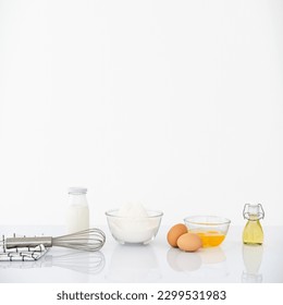 Kitchen background for mockup with eggs, rolling pin,whisk, bowl for cooking and baking utensils on table on white background . Front view, recipe theme.