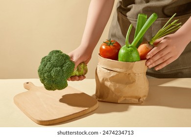 Kitchen background photo from front angle shot, a chef putting a green cabbage on a wooden chopping board, which placed on a table next to a bag of vegetable. Blank space for advertising - Powered by Shutterstock