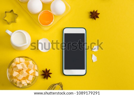 Kitchen baking mobile phone application service website mockup with eggs, butter, milk, spices anise and tools whisk, bake ware shape cookie cutter on yellow background. 