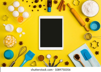 Kitchen baking tablet mobile application service website mockup with eggs butter milk floor spices cinnamon nutmeg tools whisk brush rolling pin sieve bake ware cookie cutter on yellow background